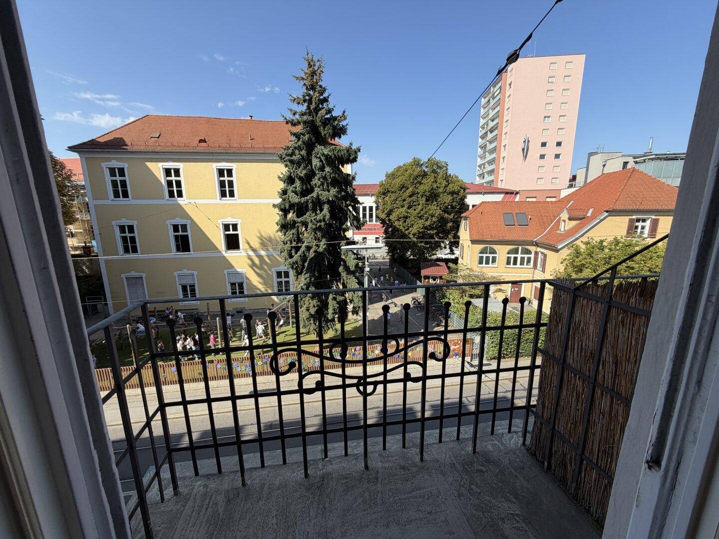Blick vom Balkon auf die umliegenden Gebäude und einen kleinen Spielplatz.