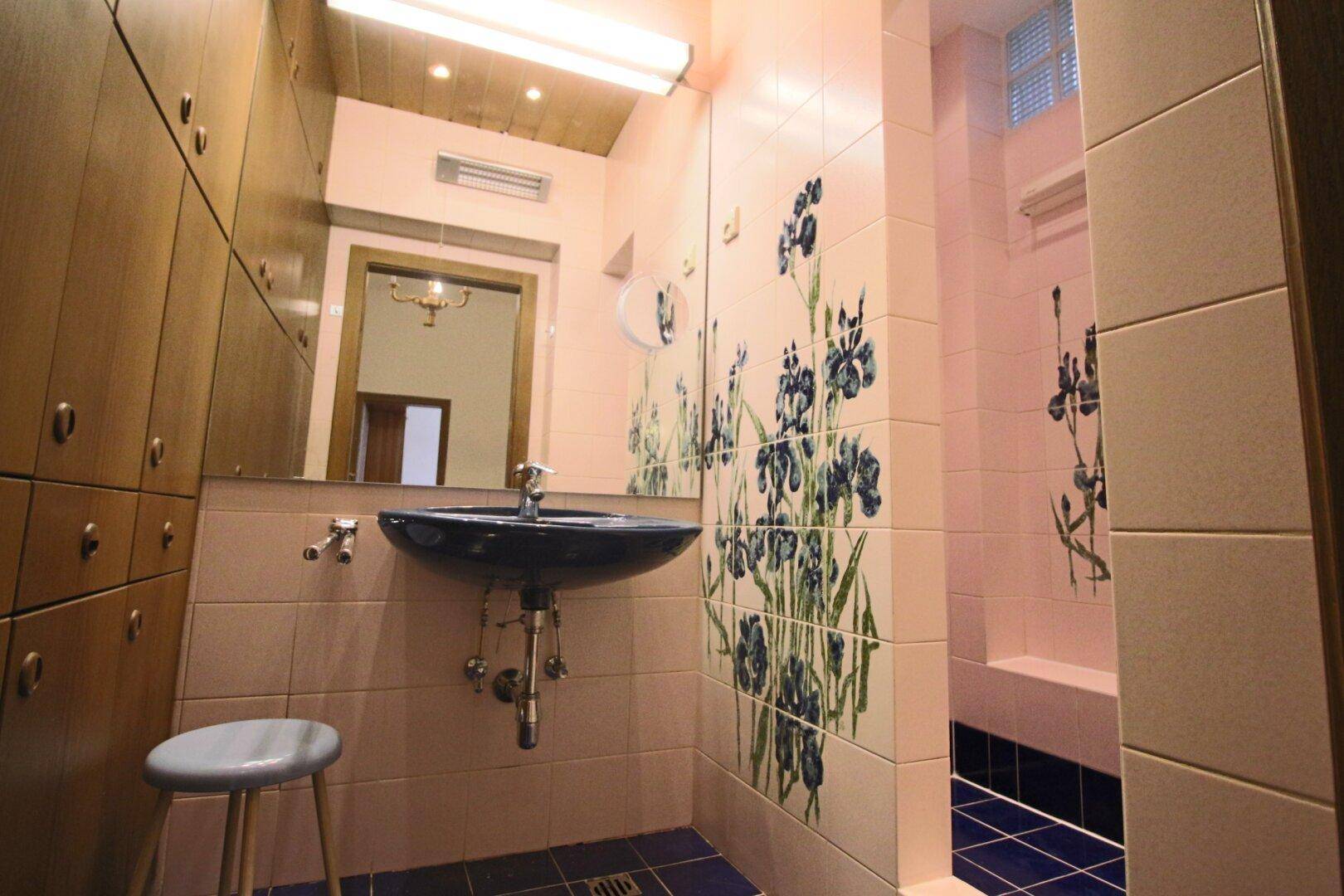 Badezimmer mit rosa Fliesen, blauer Keramik und integrierter Dusche.