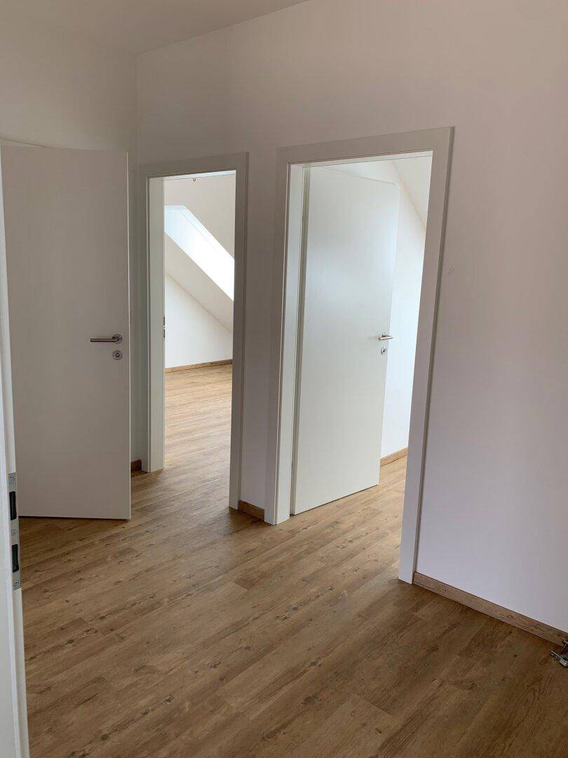 Heller Bereich mit Laminatboden und offenen Türen, die den Zugang zu weiteren Räumen ermöglichen.