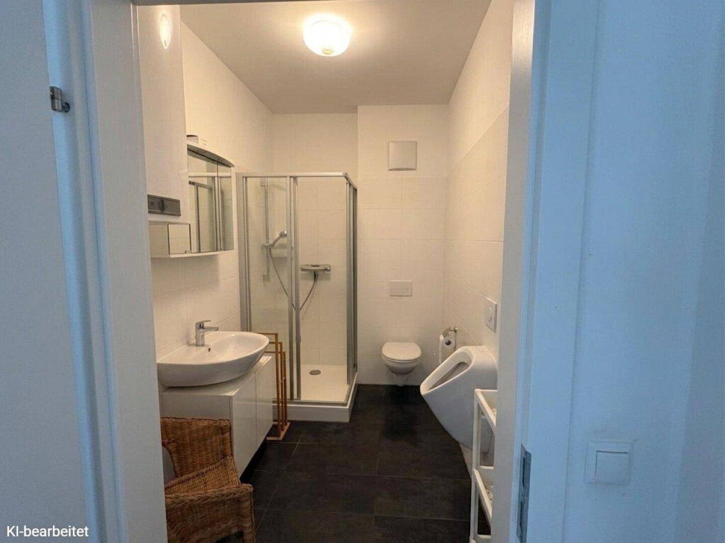 Modernes Badezimmer mit Dusche, Waschbecken, WC und Urinal in hellen Farben.