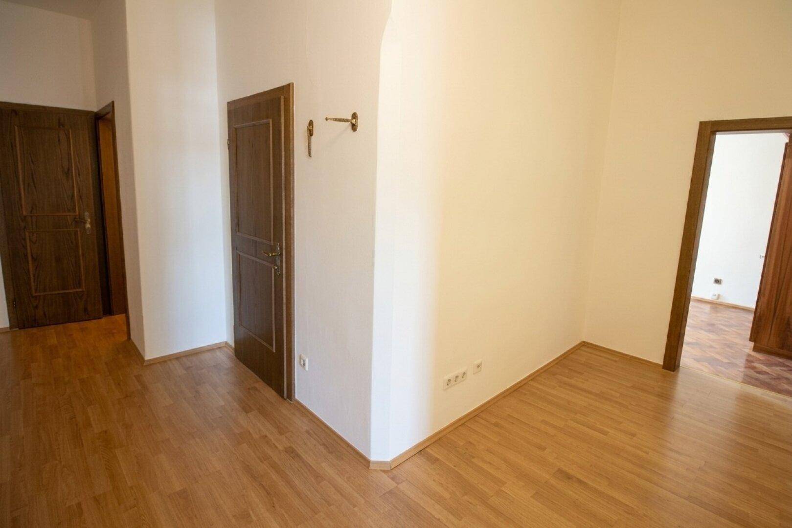 Flur mit Laminatboden und mehreren Holztüren, die zu verschiedenen Räumen führen.