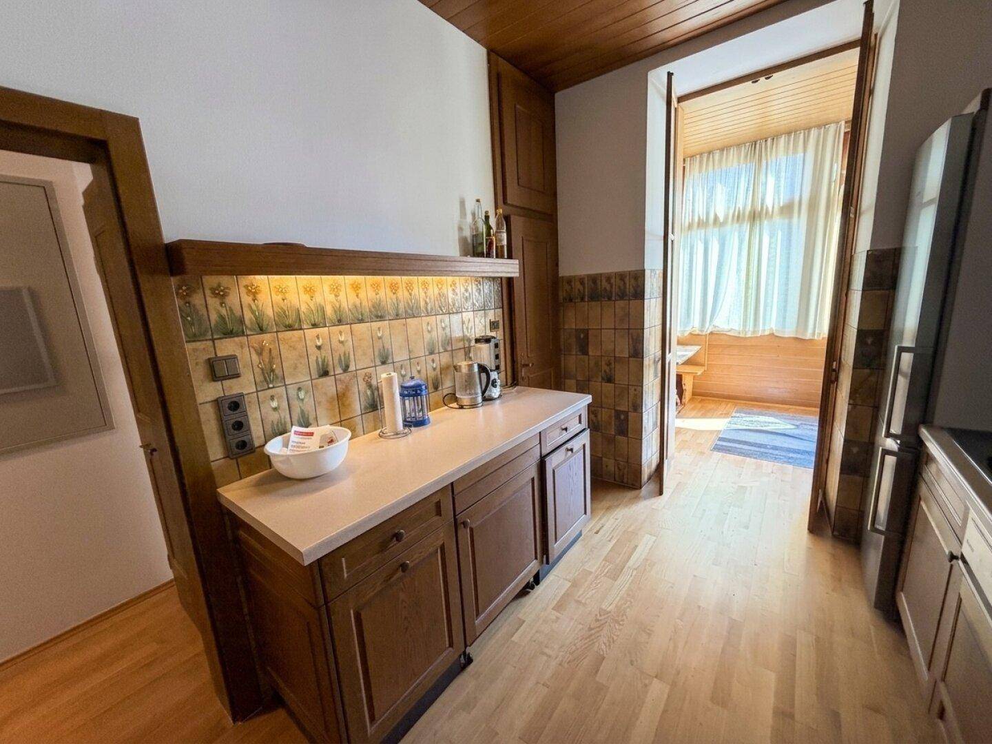 Gemütliche Küche mit Holzelementen, Arbeitsplatte und Blick in einen weiteren Raum.