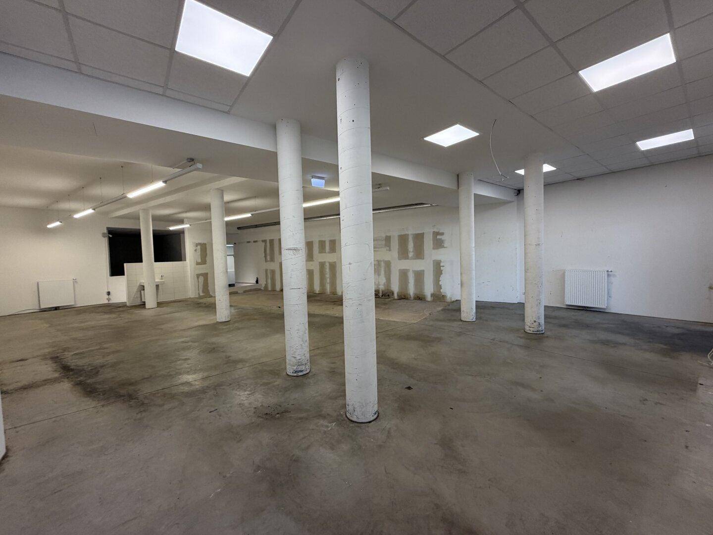 Weitläufiger, heller Raum mit vielen Säulen, weißen Wänden und Betonboden, bereit zur individuellen Gestaltung.