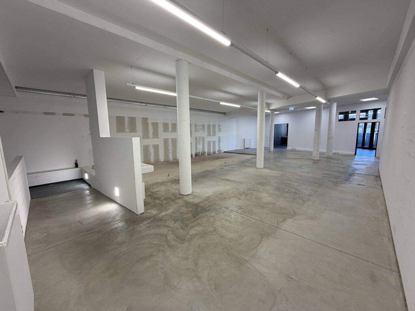 Heller, offener Raum mit Betonboden und weißen Wänden, bietet viel Potenzial für verschiedene Nutzungen.