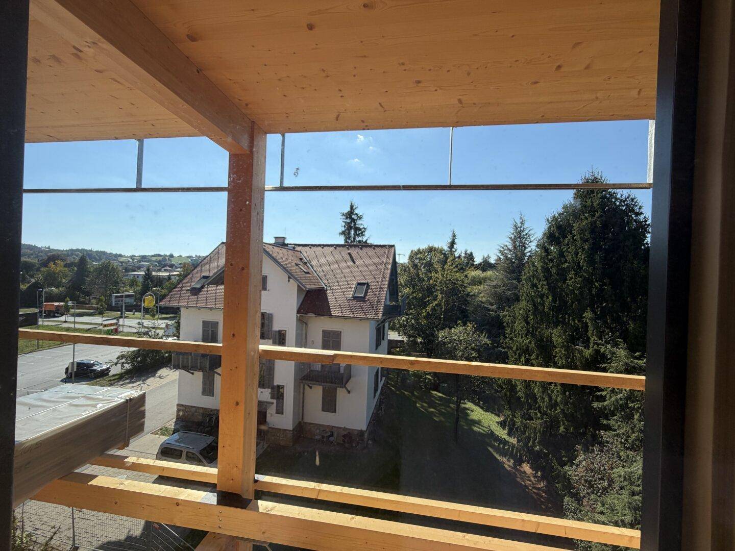 Blick vom im Bau befindlichen Balkon auf die umliegende Bebauung und grüne Landschaft.