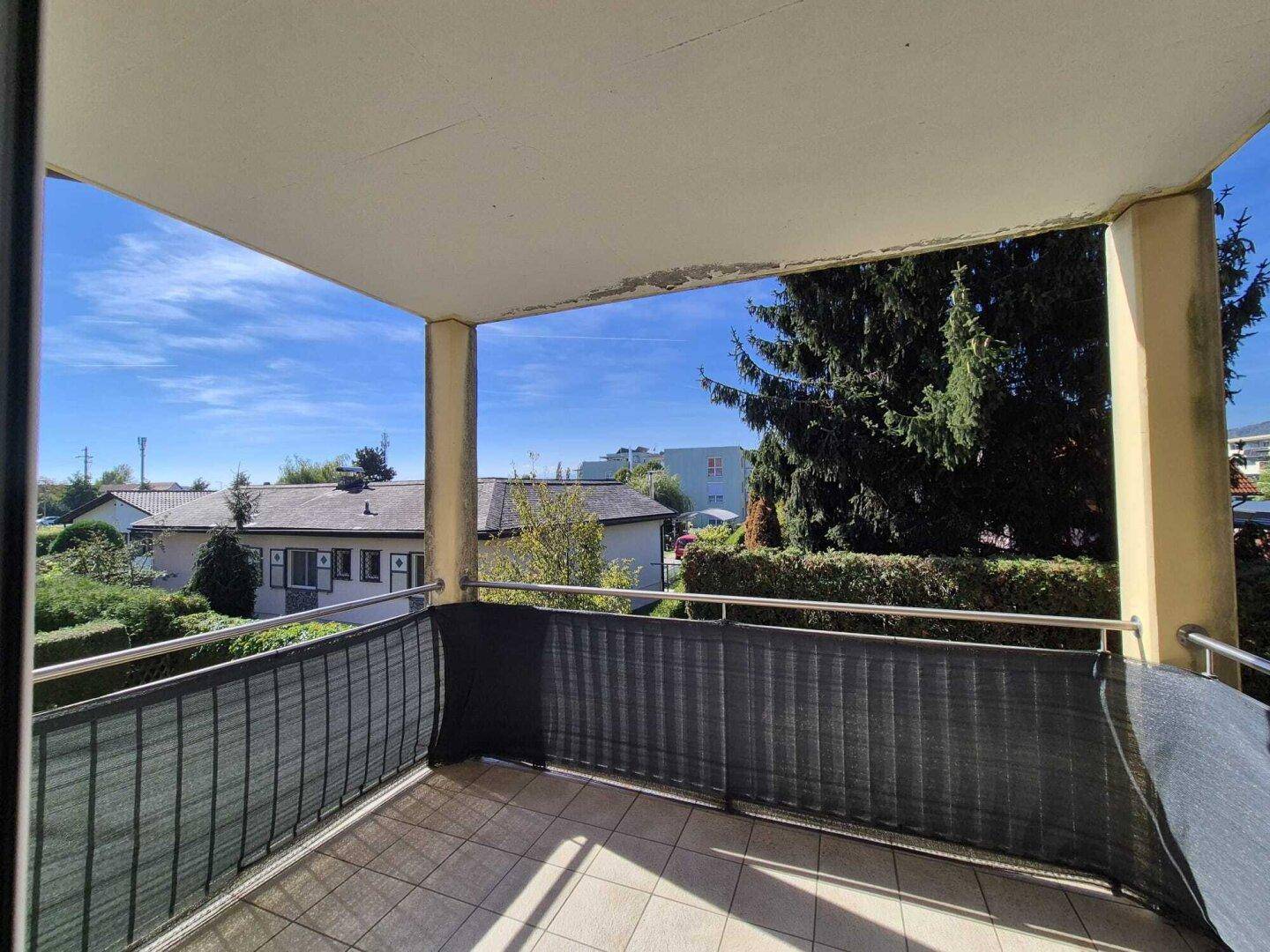 Sonniger Balkon mit weitem Blick über die Nachbarschaft und viel Grün, ideal zum Entspannen.