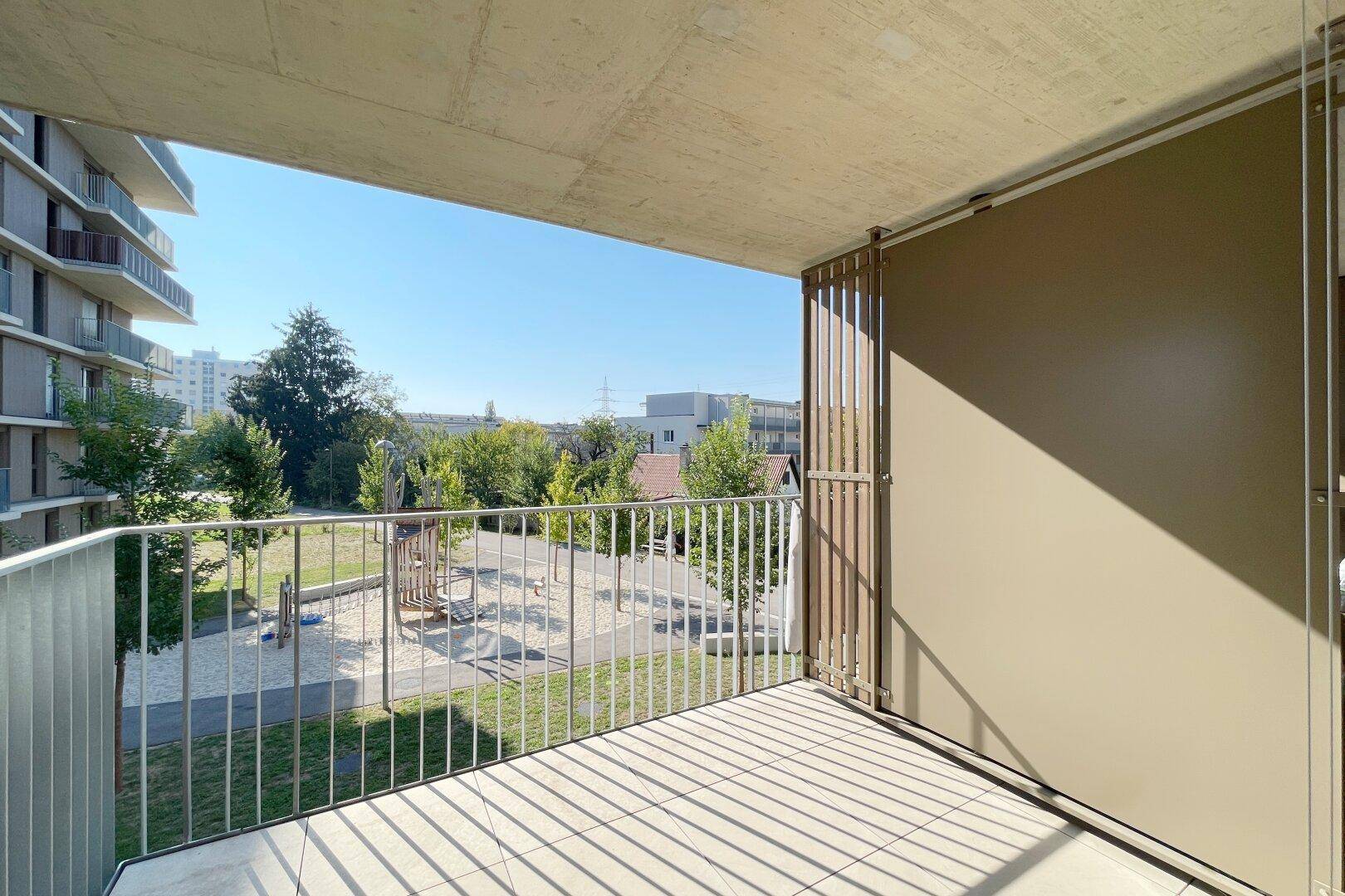 Geräumiger Balkon mit Blick auf einen Kinderspielplatz und die umliegende Grünfläche.