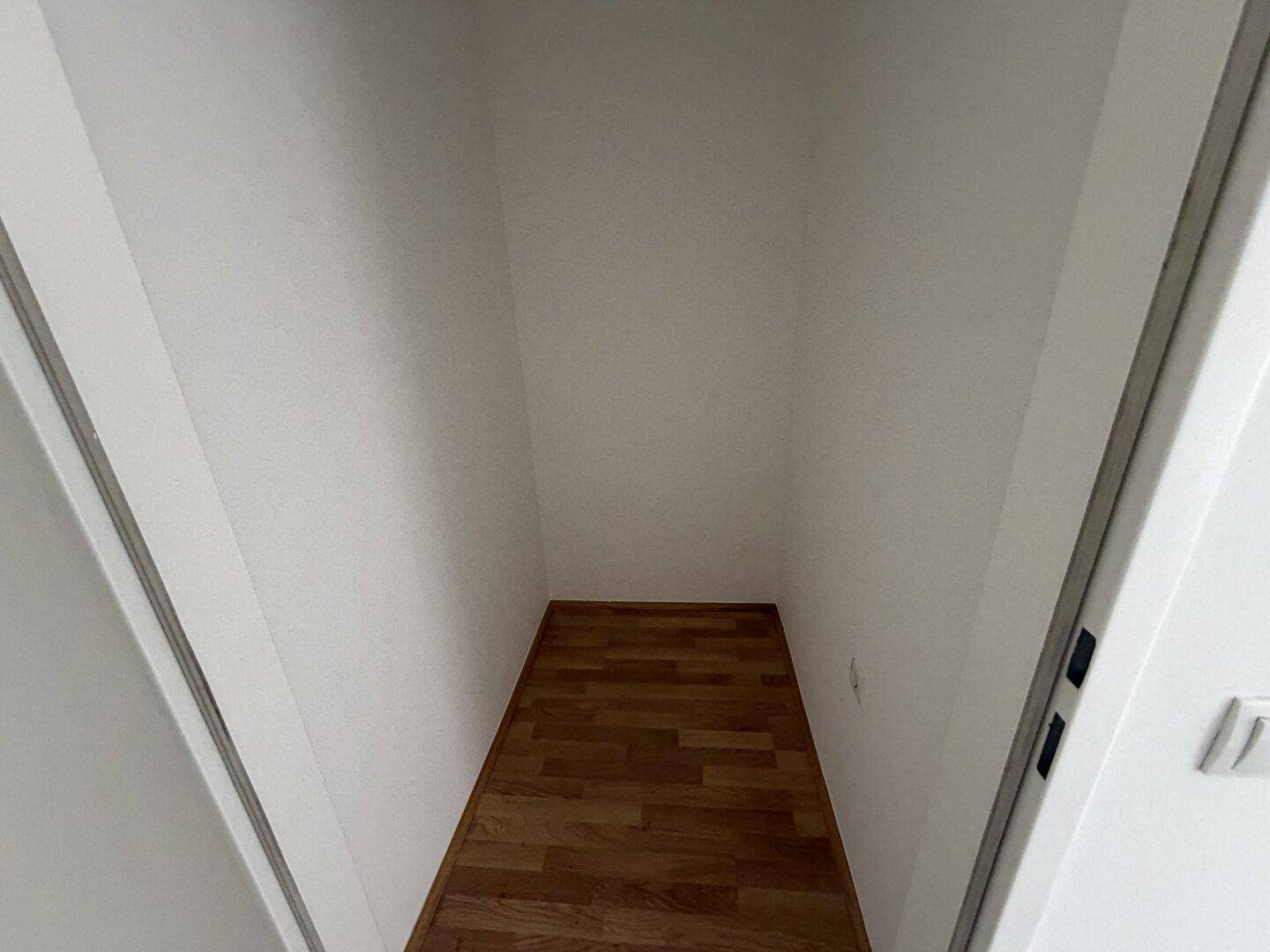 Kleiner, leerer Abstellraum mit Laminatboden und weißen Wänden für zusätzlichen Stauraum.