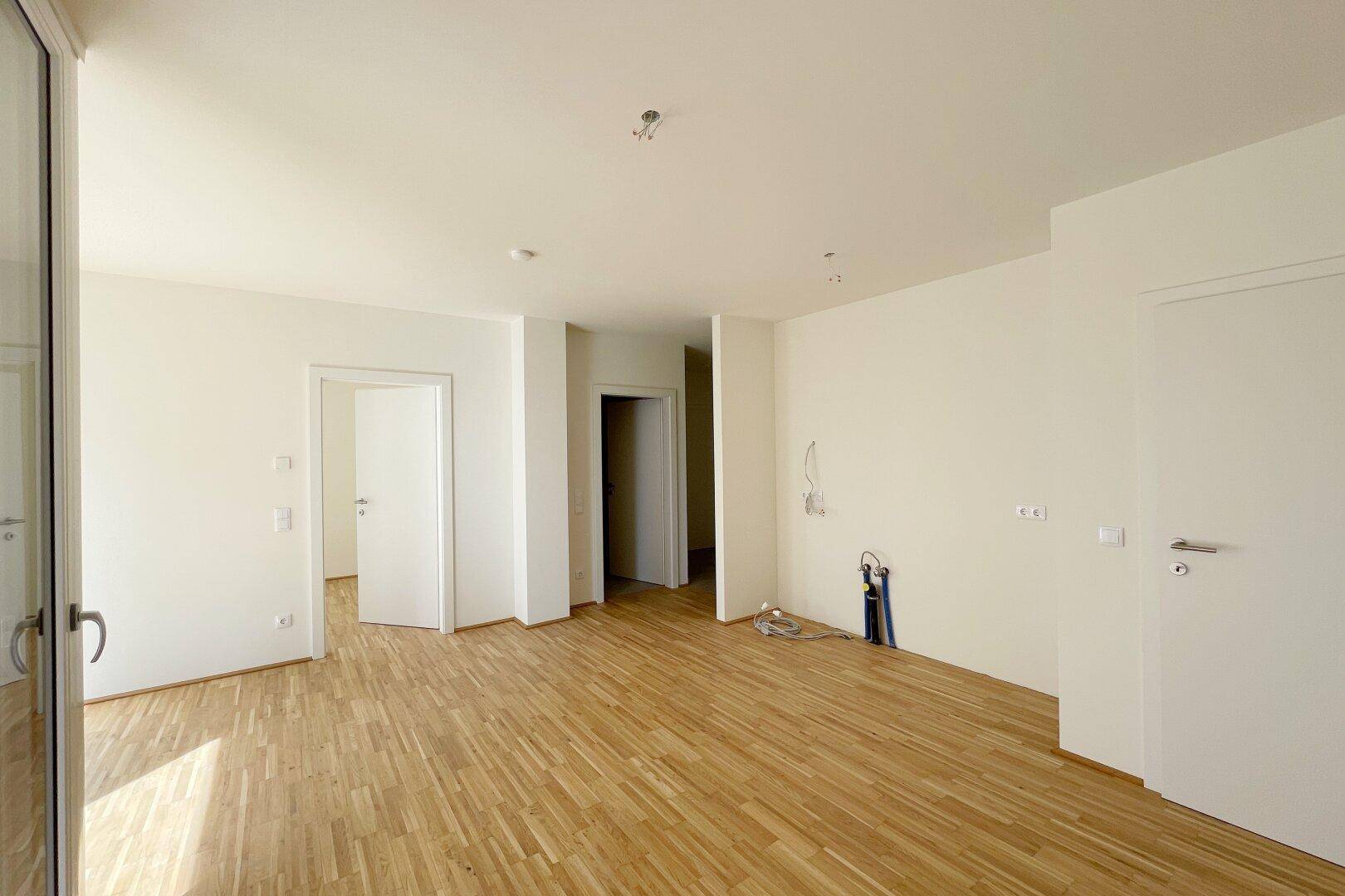 Geräumiger Flurbereich mit Holzboden und mehreren Türen, der verschiedene Räume miteinander verbindet.