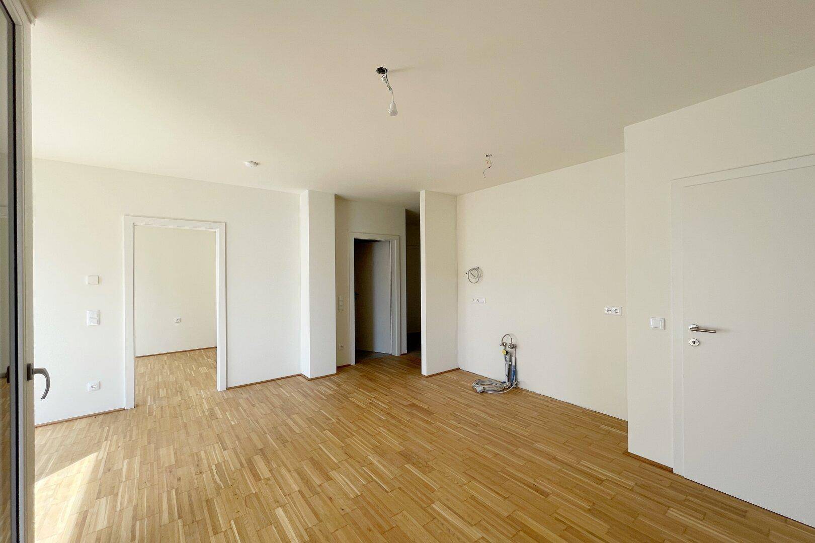 Geräumiger, heller Wohnbereich mit Parkettboden und Zugang zu weiteren Zimmern.
