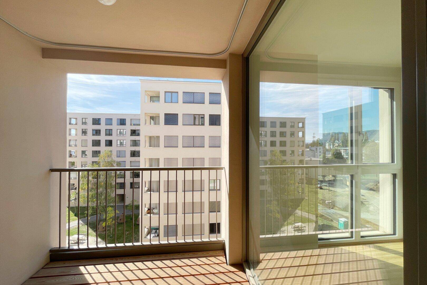 Blick vom Balkon auf die umliegenden modernen Wohngebäude und den grünen Innenhof.