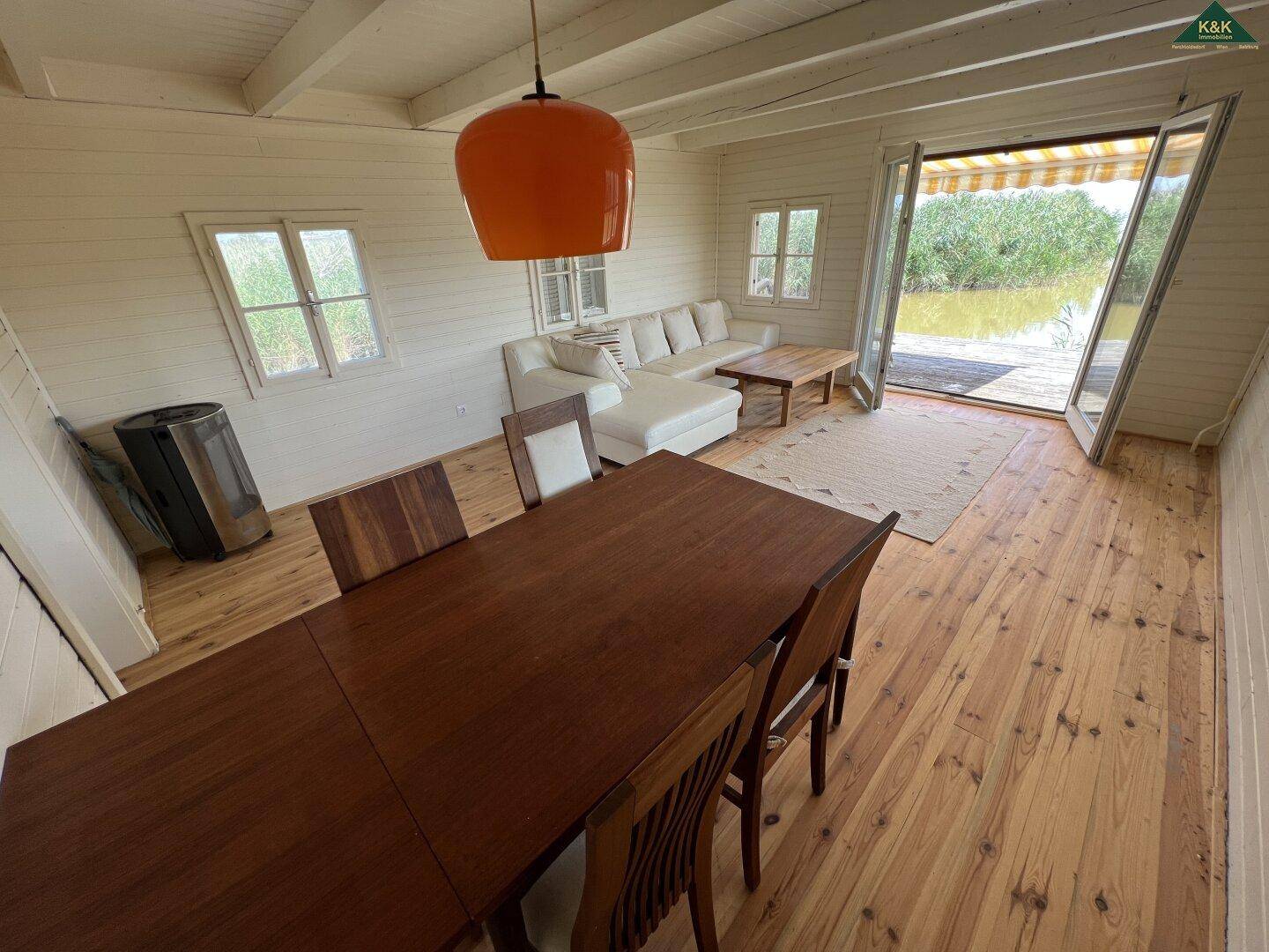 Heller Wohn- und Essbereich mit Holzboden, Esstisch und Sofa, mit direktem Zugang zur Terrasse.
