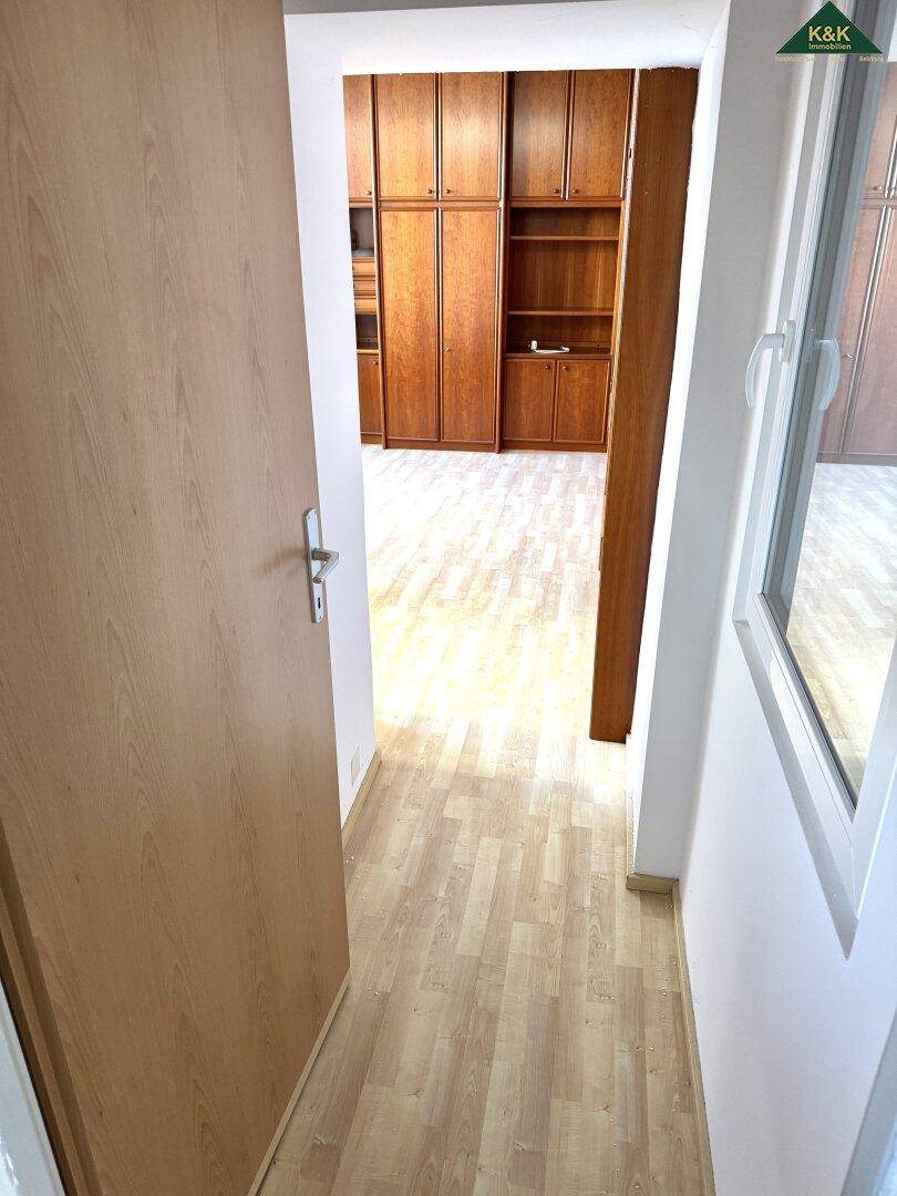 Heller Flur mit Laminatboden und Blick in ein weiteres Zimmer.