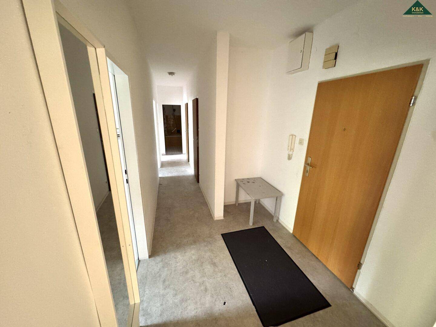 Langer Flur mit Teppichboden und Zugang zu verschiedenen Zimmern, hell und funktional.