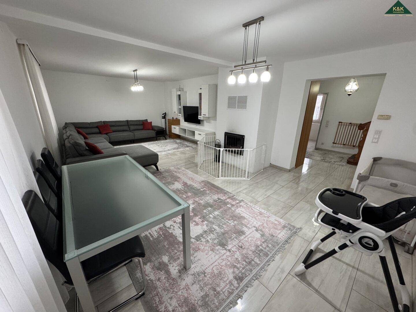 Offener Wohn-Essbereich mit hellem Fliesenboden, Esstisch und großem Sofa, ideal für Familien.