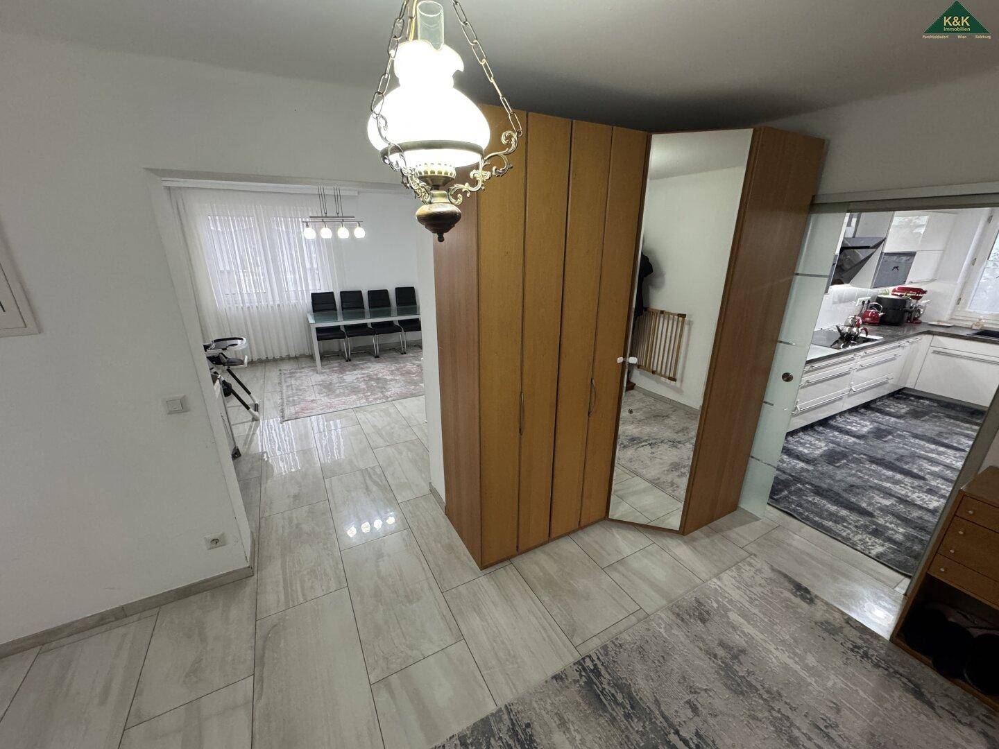Flur mit Holzschrank und Spiegel, der zum Wohnbereich und zur Küche führt.