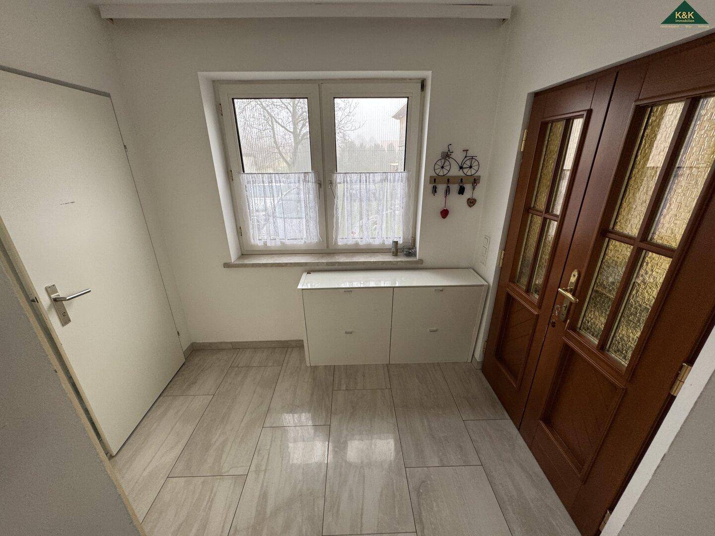 Heller Eingangsbereich mit Fenster und Haustür, bietet natürlichen Lichteinfall.