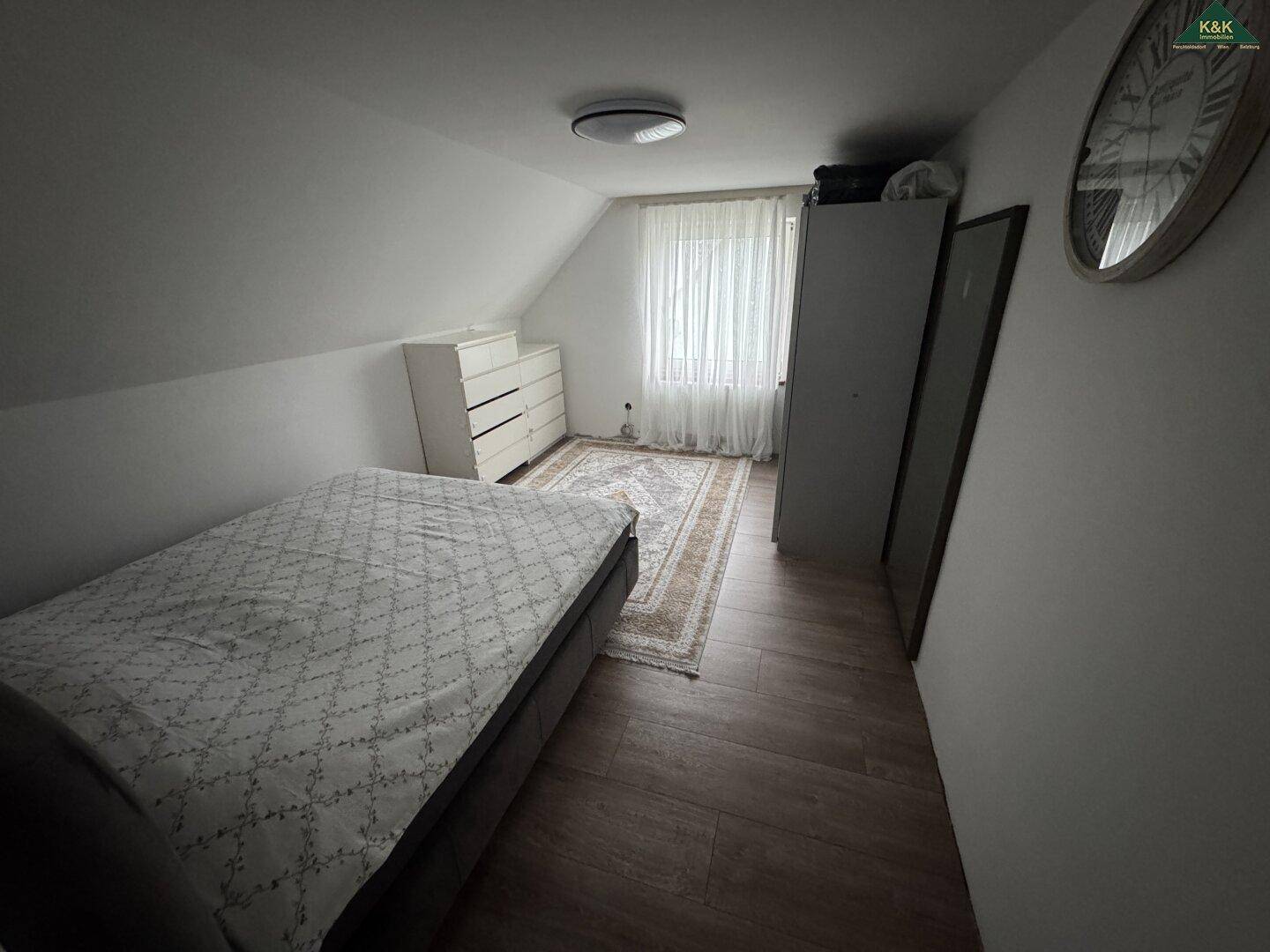 Schlafzimmer im Dachgeschoss mit schrägen Wänden und Fenster für natürliches Licht.