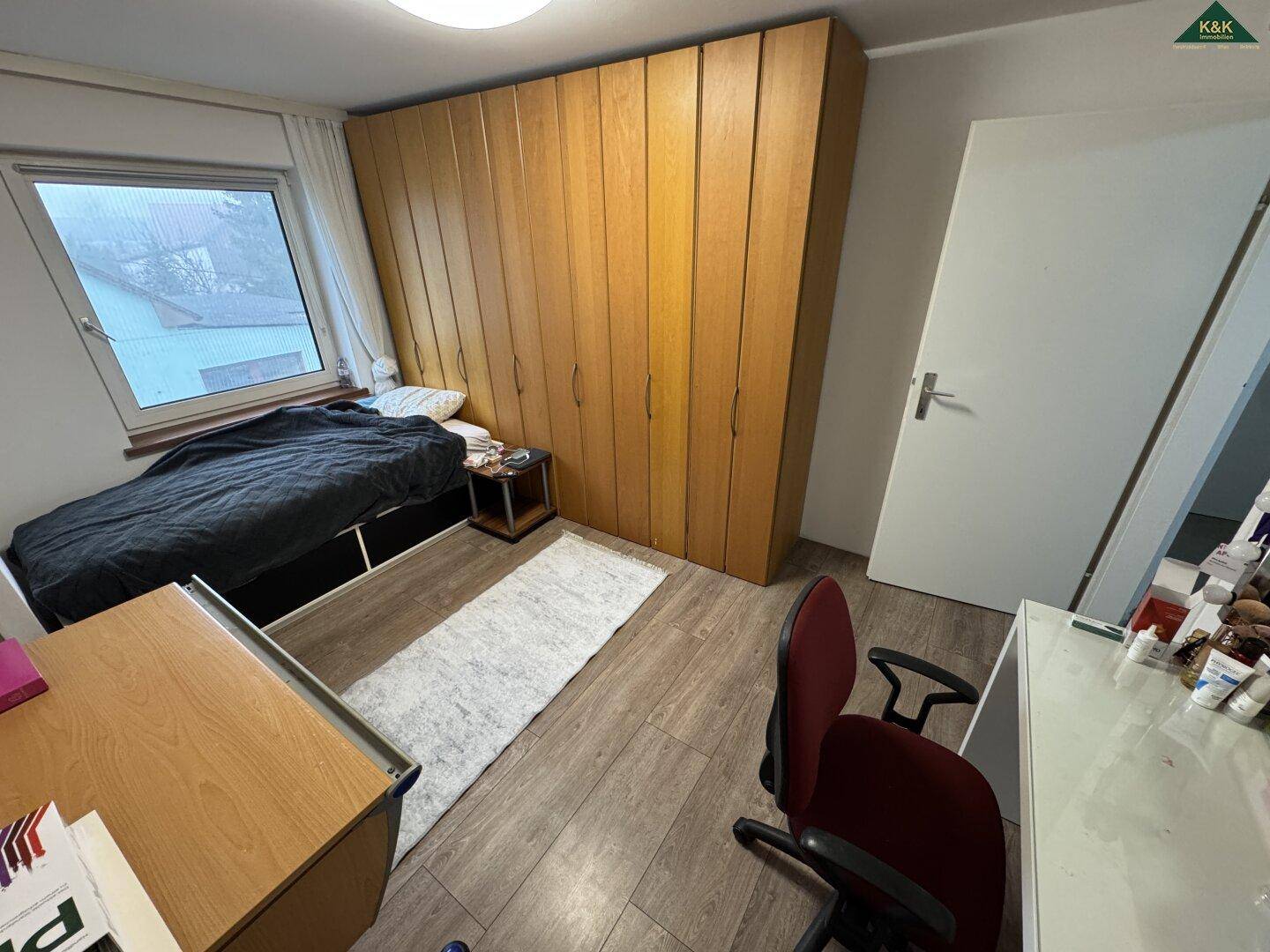 Helles Zimmer mit großem Holzschrank, Bett und Schreibtisch, ideal für Kinder oder Büro.