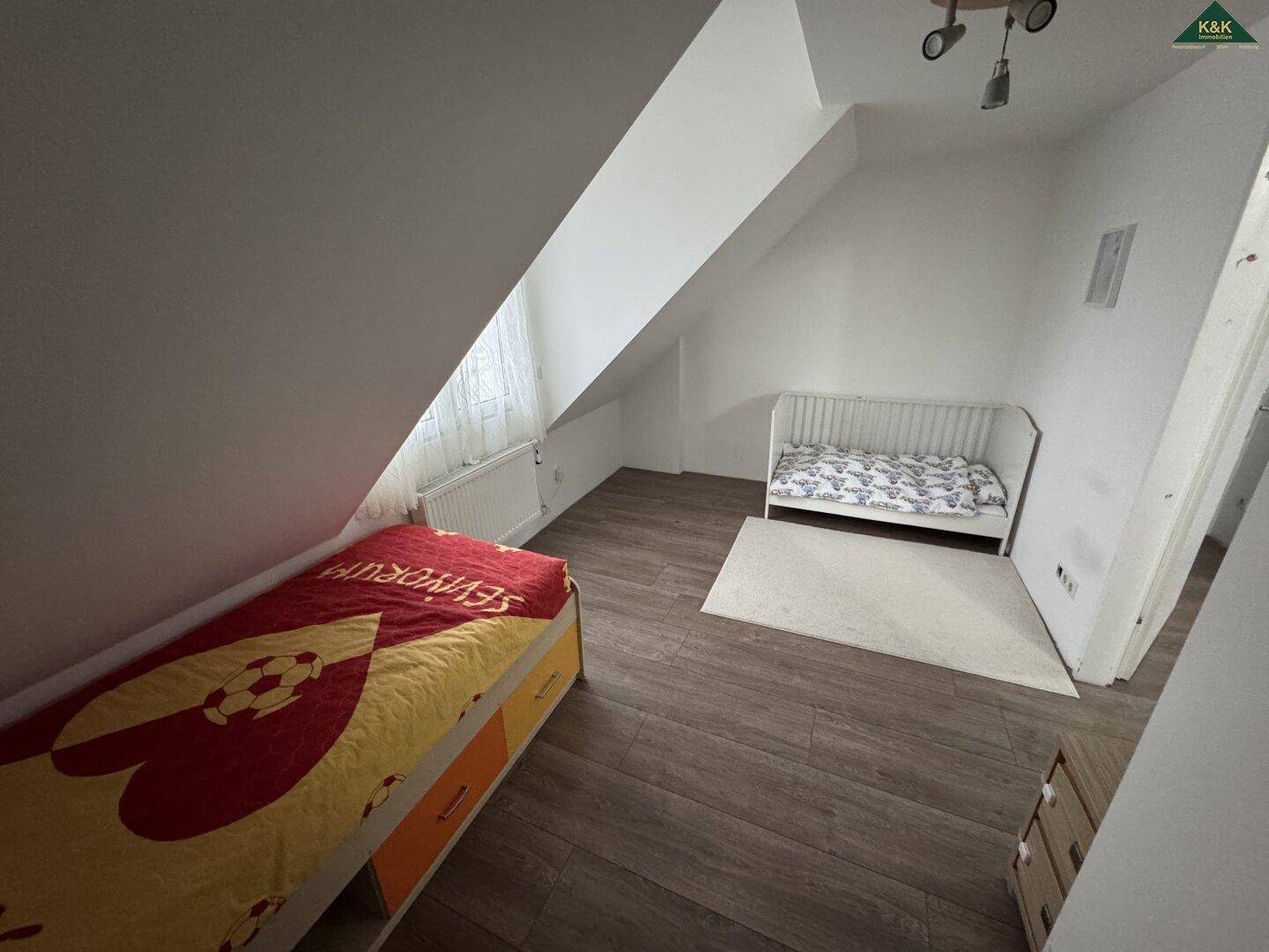 Geräumiges Kinderzimmer im Dachgeschoss mit zwei Betten und viel Platz zum Spielen.