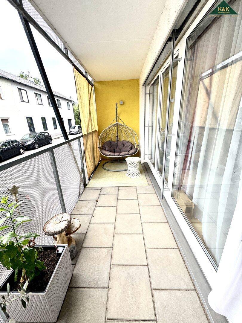 Gemütlicher Balkon mit Hängesessel und Fliesenboden, ideal zum Entspannen im Freien.