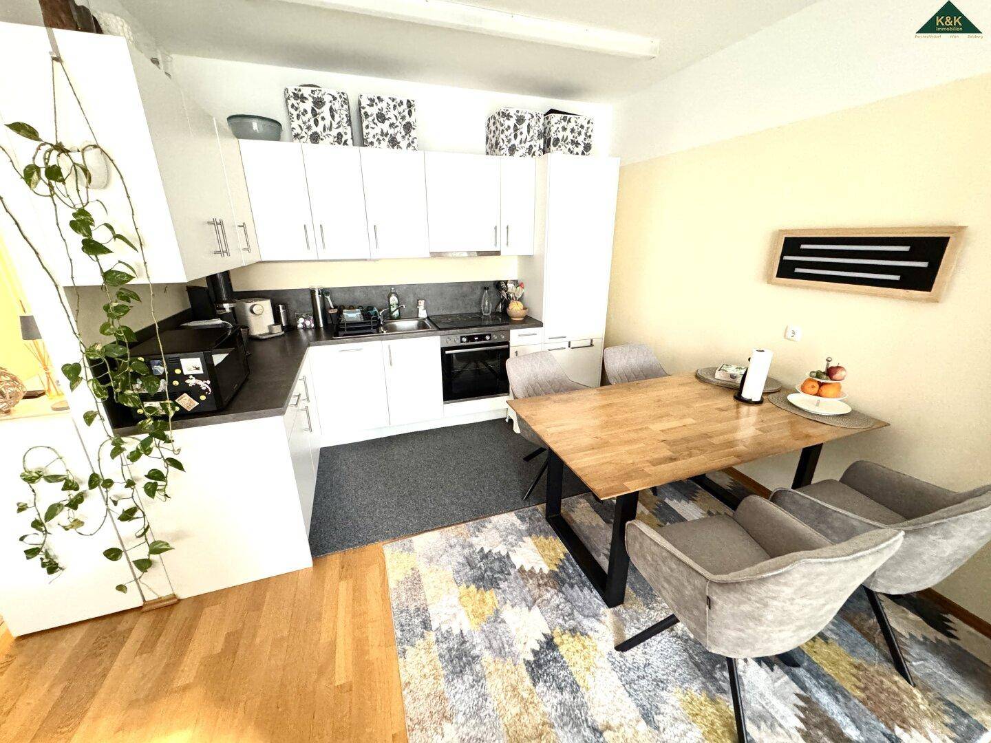 Funktionale Küche mit weißen Schränken und Essbereich, ausgestattet mit einem Holztisch.