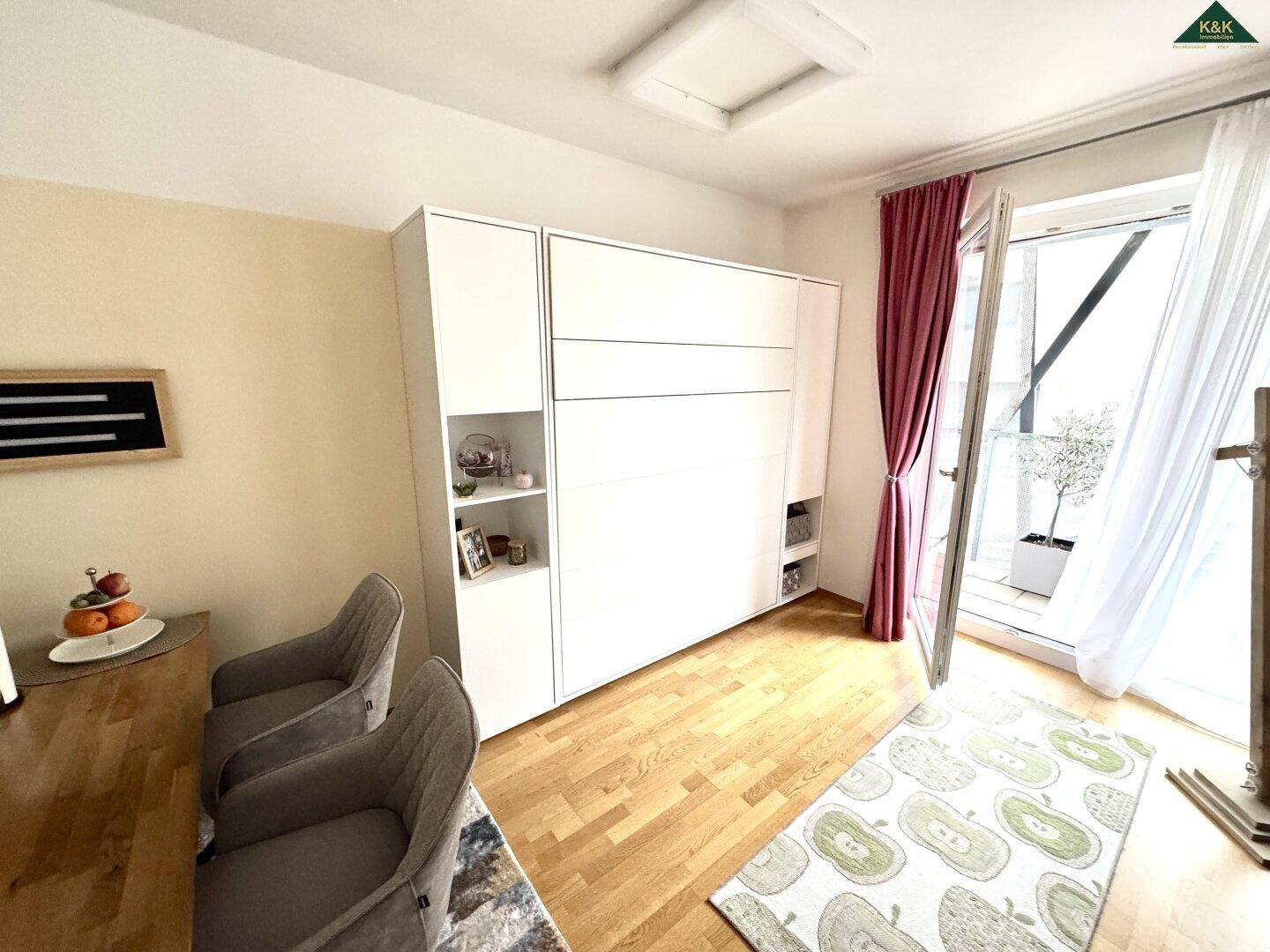 Essbereich mit Holztisch und Stühlen, angrenzend an einen Schrank und mit Balkonzugang.