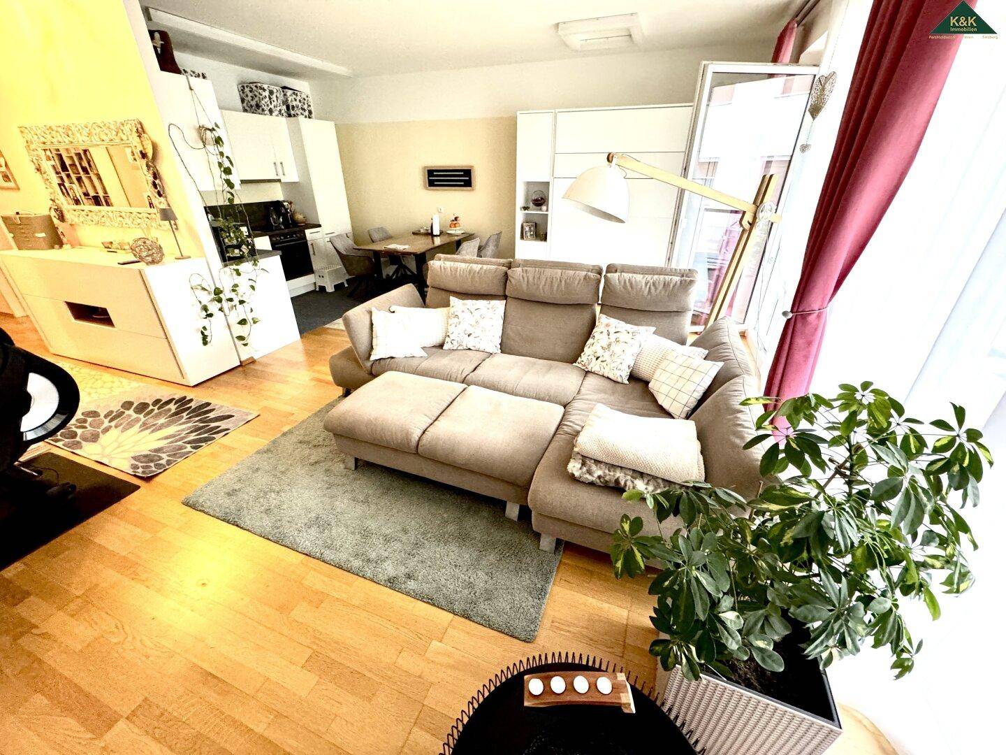 Offener Wohnbereich mit beigem Sofa, Essbereich und Blick auf die angrenzende Küche.
