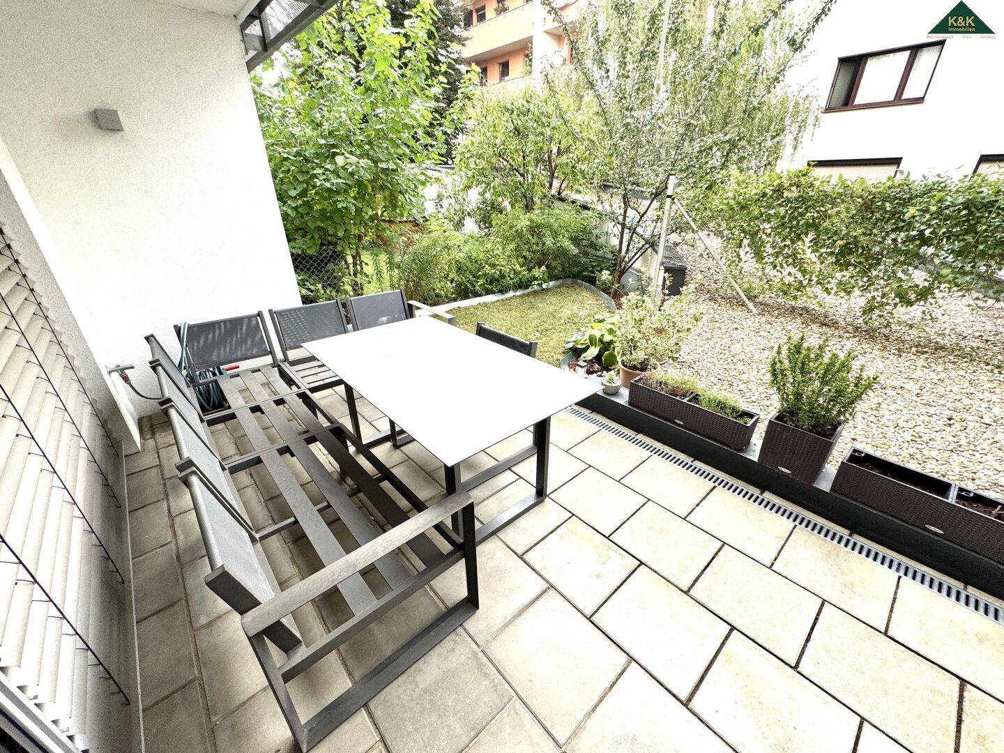 Geräumige Terrasse mit Essbereich und Blick auf den begrünten Gartenbereich des Anwesens.