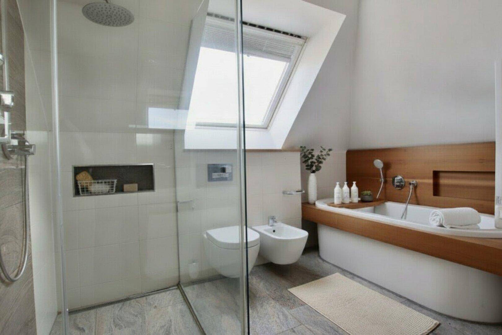 Modernes Badezimmer mit Badewanne, Dusche, Bidet und Dachfenster für natürliches Licht.