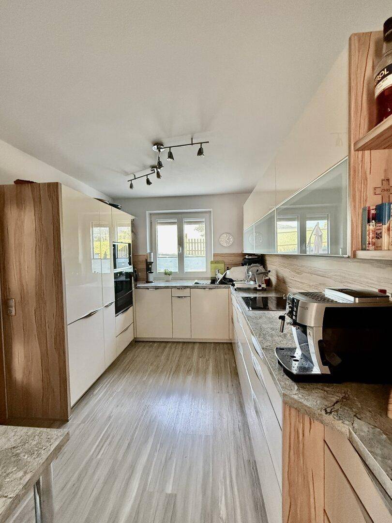 Moderne Küche mit hellen Holz- und Hochglanzfronten, Granitarbeitsplatte und Fenster.