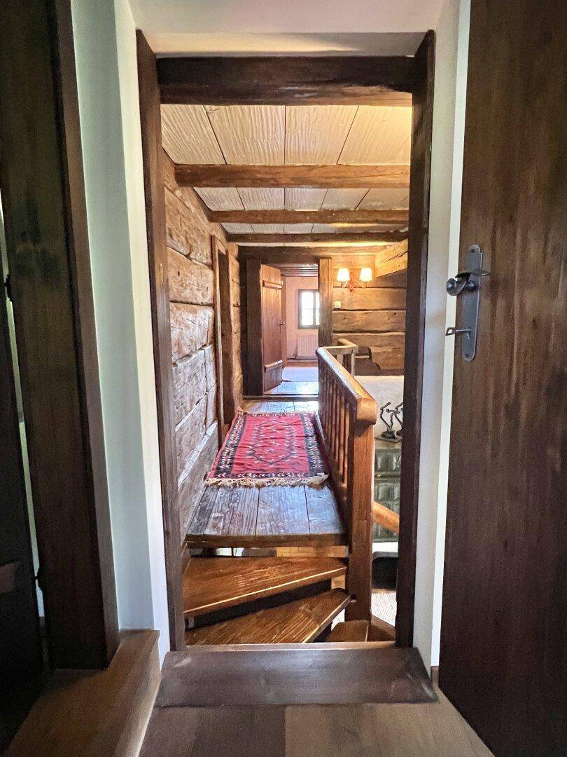 Rustikaler Flur mit Holzwänden, sichtbaren Balken und einer charmanten Holztreppe zum Obergeschoss.