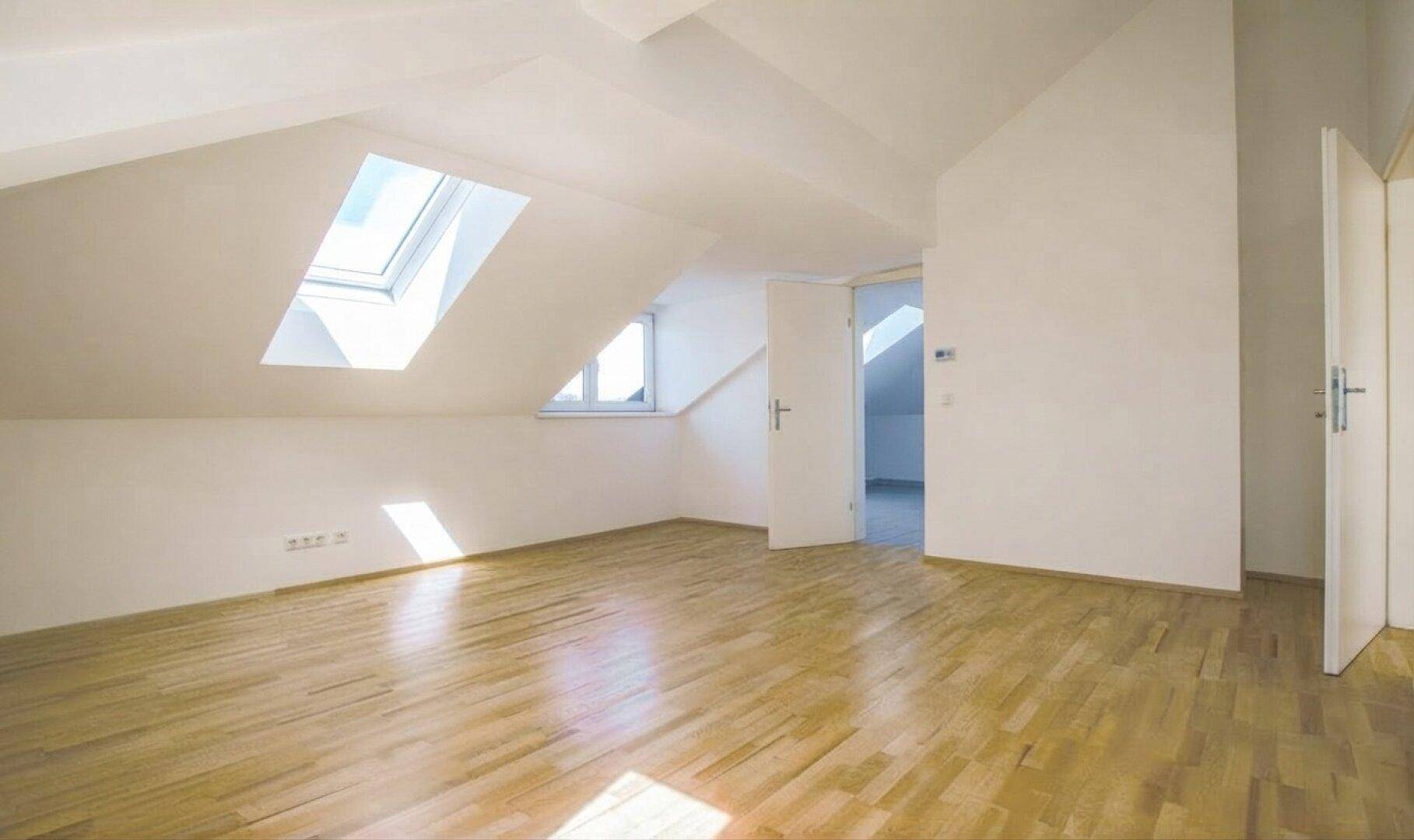 Geräumiges Schlafzimmer im Dachgeschoss mit Parkettboden, Dachschrägen und viel natürlichem Licht.