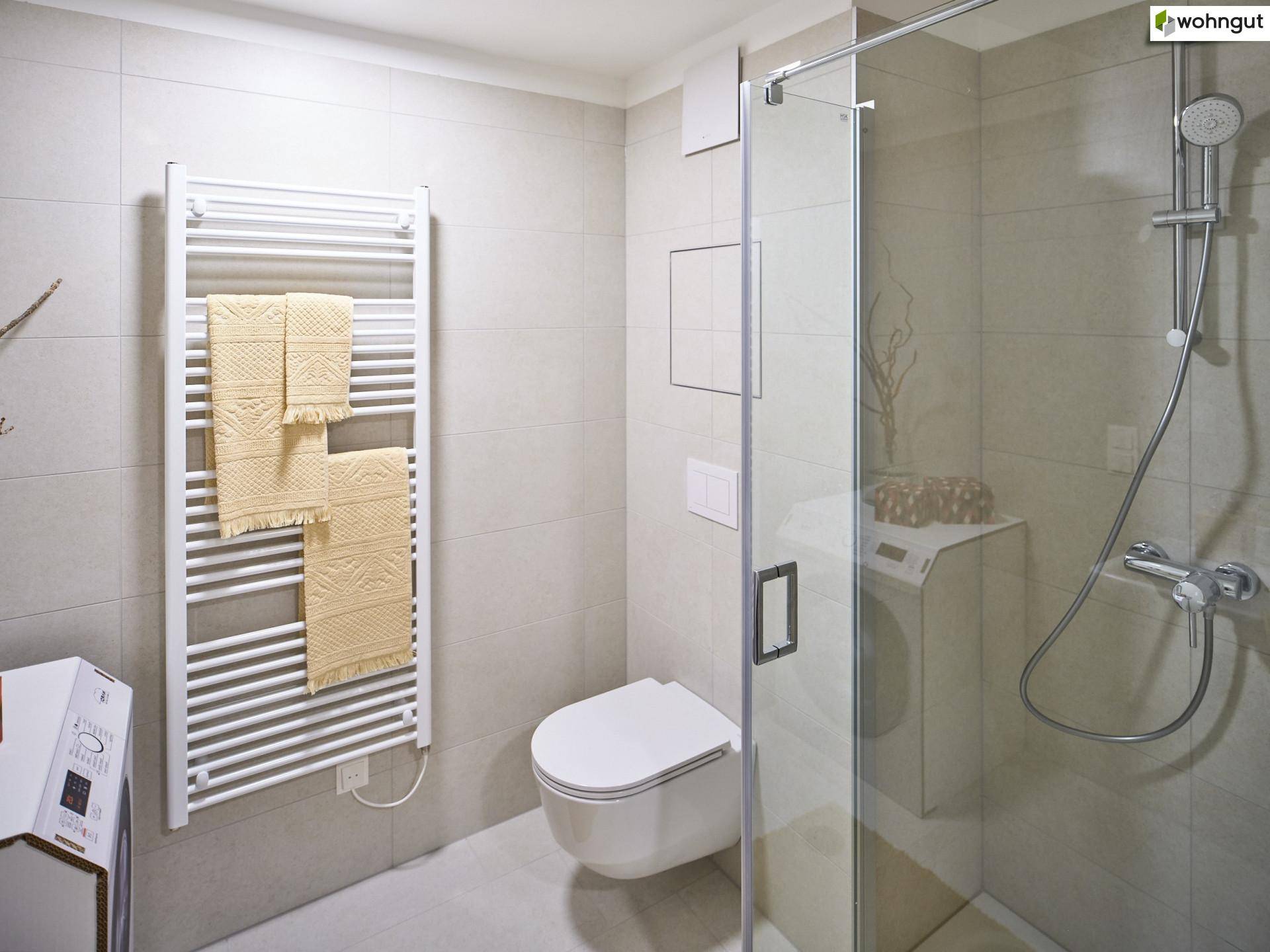 Modernes Badezimmer mit Duschkabine, wandhängendem WC und beheiztem Handtuchhalter.
