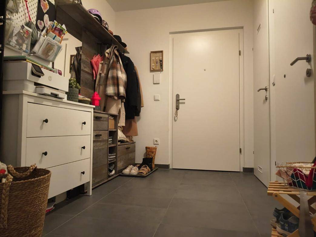 Eingangsbereich mit dunklen Fliesen, Garderobe und einer weißen Eingangstür.
