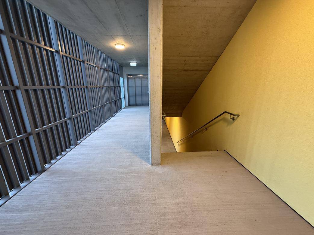 Moderner Treppenaufgang und Flur mit Betonwänden und Metallgeländer in einem neuen Gebäude.