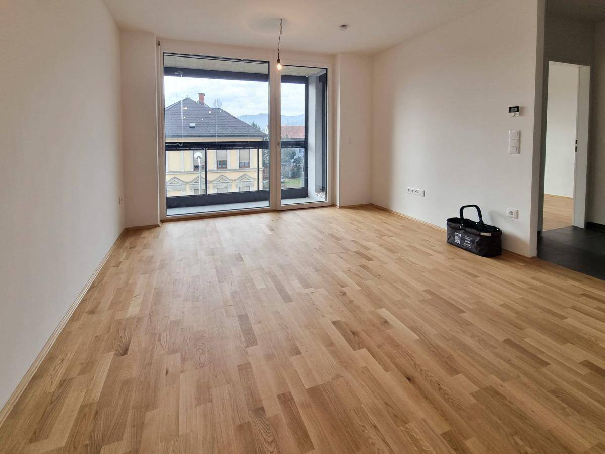 Heller Wohnbereich mit großen Fenstern, Holzboden und Blick auf die Stadt.