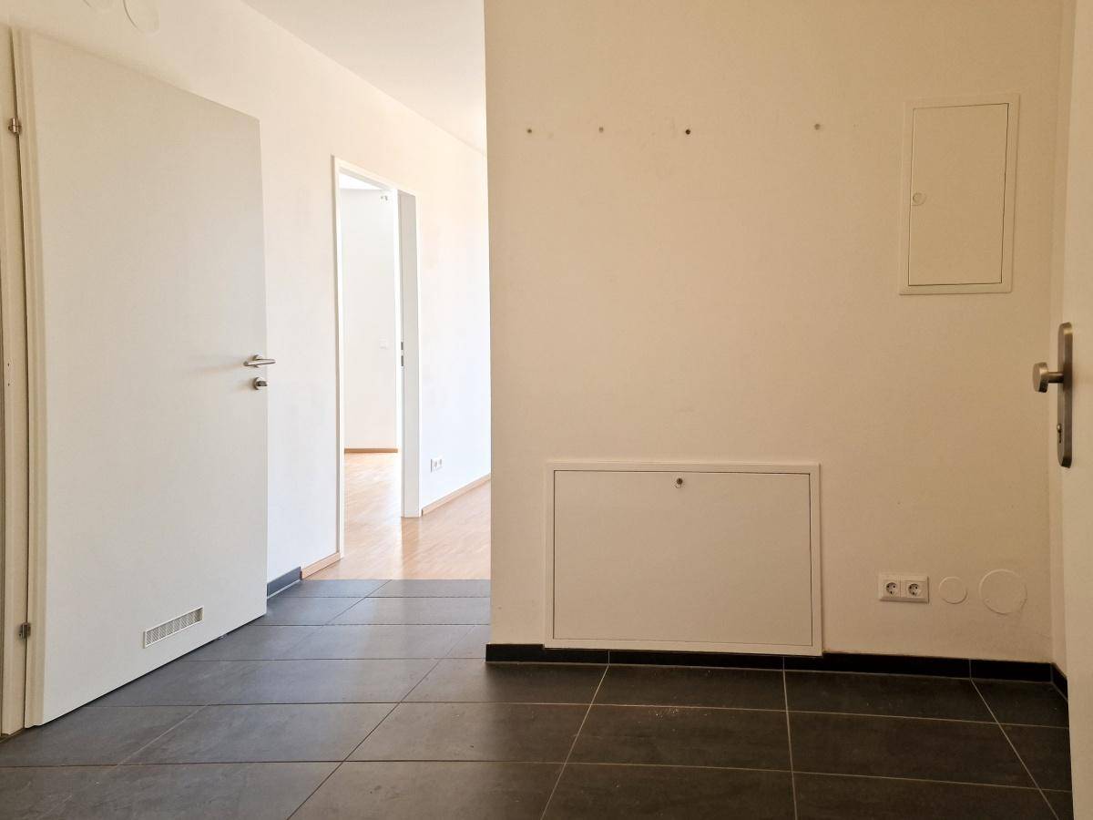 Heller Flur mit dunklen Fliesen und Zugang zu weiteren Räumen.