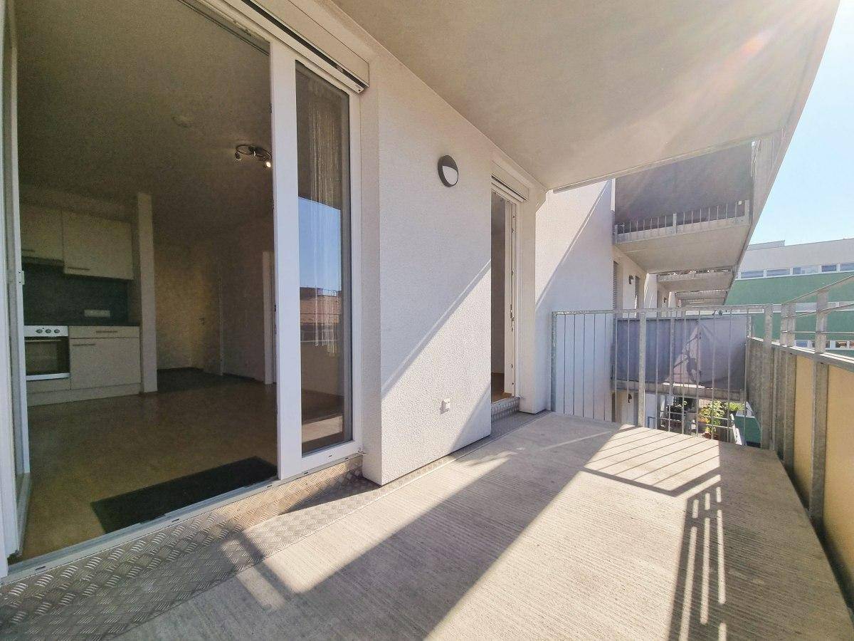 Sonniger Balkon mit Blick auf die Umgebung und Zugang zur Wohnung.