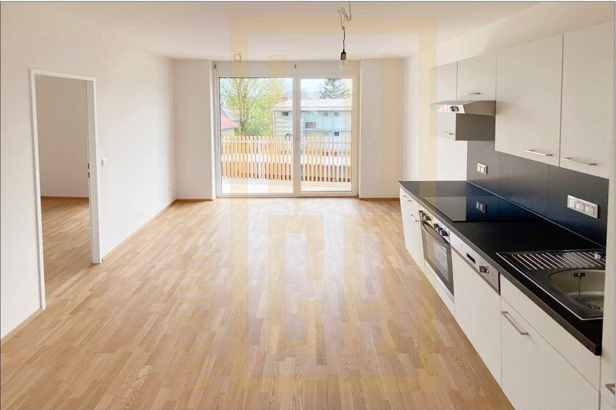Offener Wohnbereich mit integrierter Küche, Parkettboden und Zugang zum Balkon.