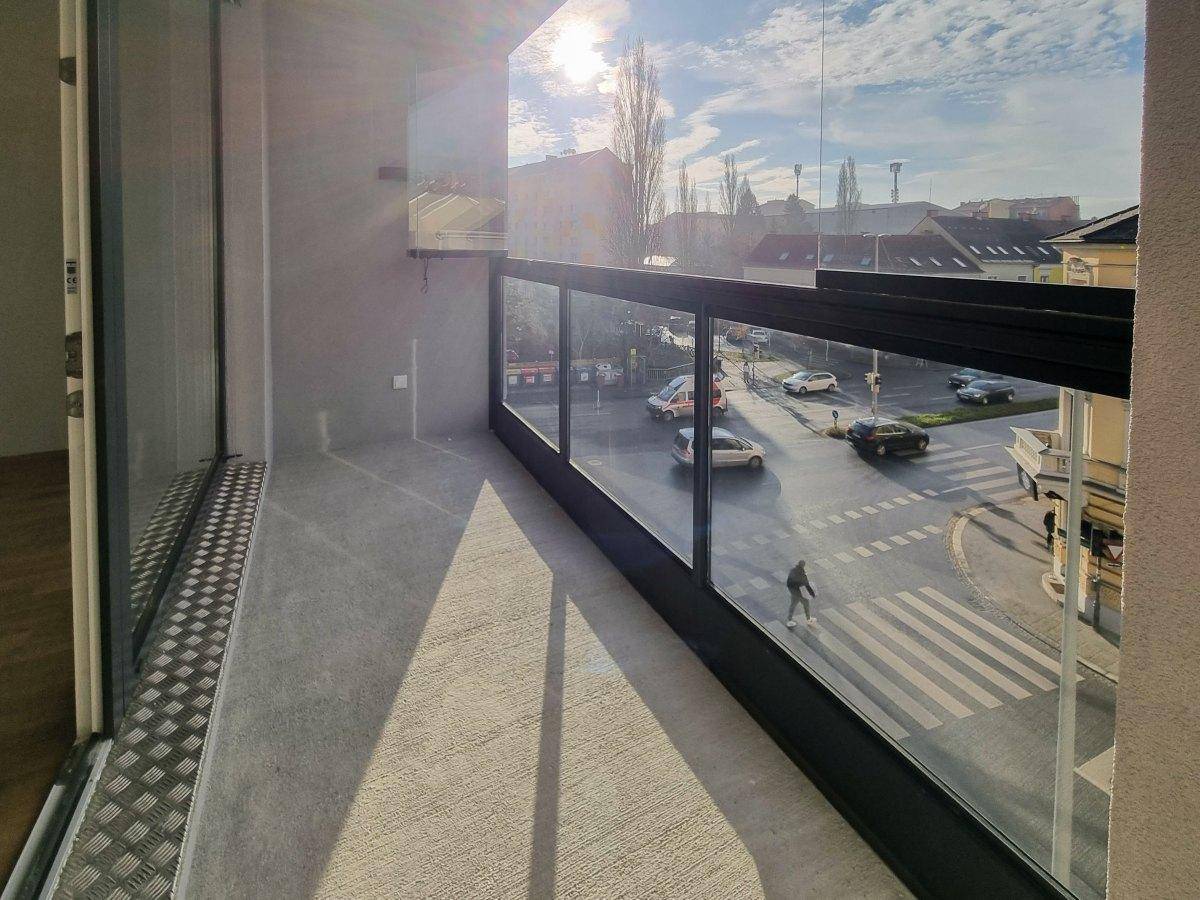 Verglaste Loggia mit sonnigem Ausblick auf die belebte Straße und die Umgebung.