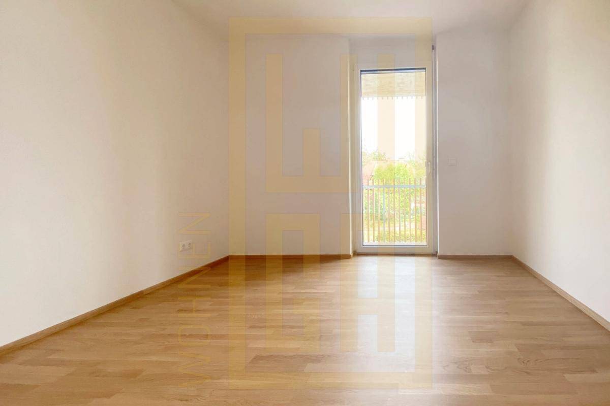 Helles Zimmer mit Parkettboden und Balkonzugang, bereit zur individuellen Gestaltung.