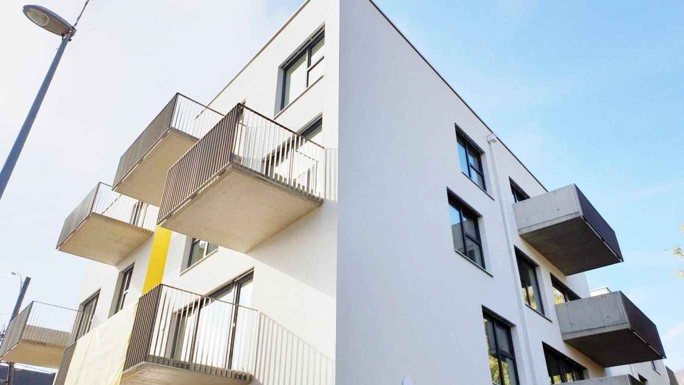 Moderne Gebäudefassade mit mehreren auskragenden Balkonen unter blauem Himmel.