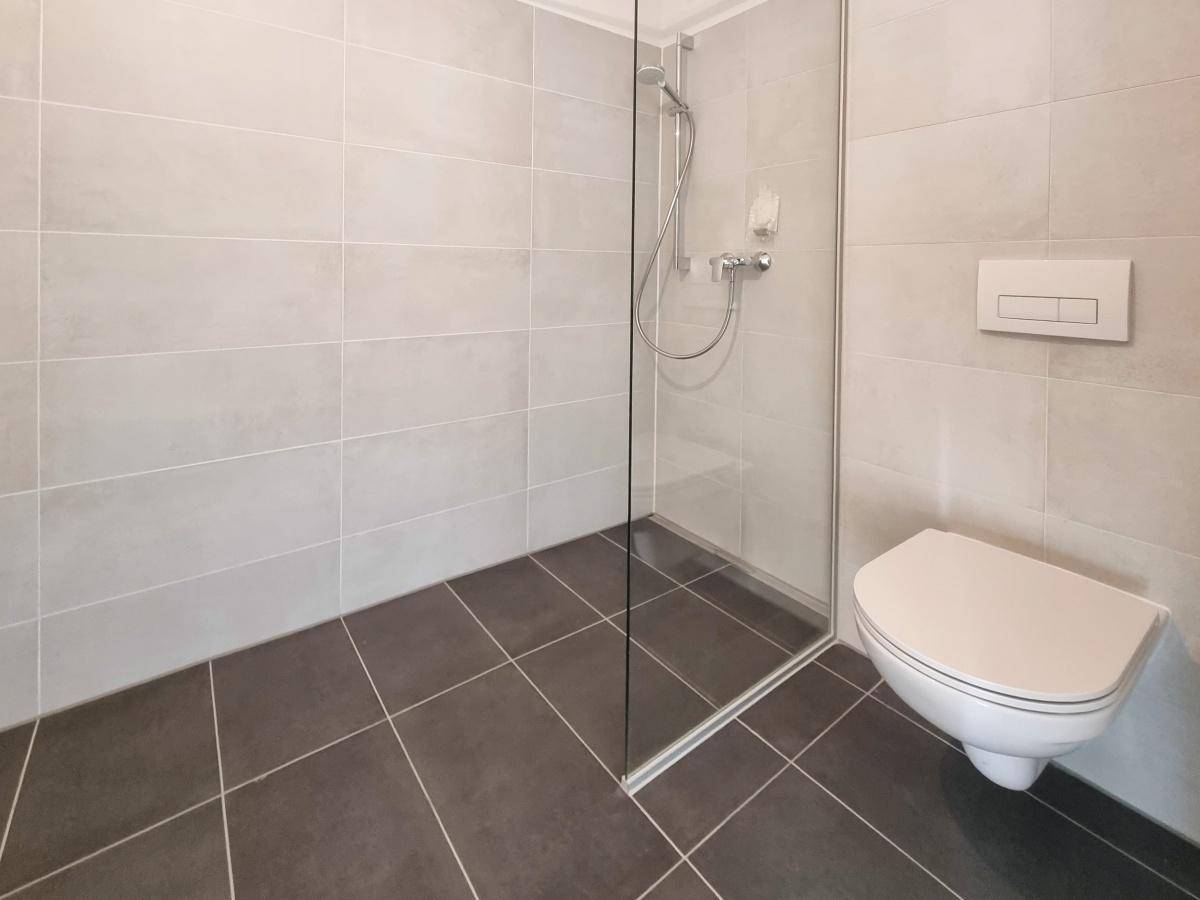 Modernes Badezimmer mit ebenerdiger Dusche und wandhängendem WC.