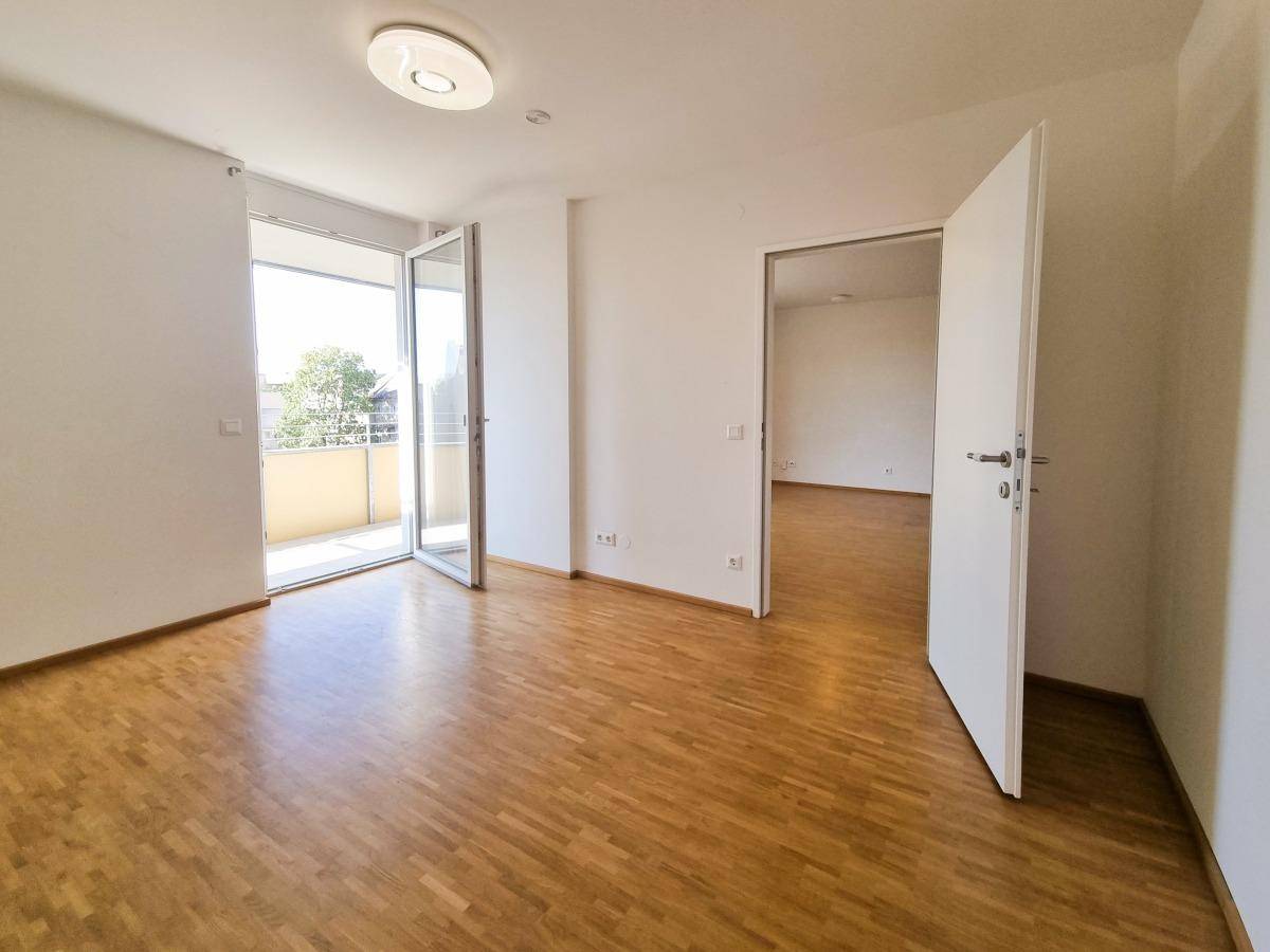 Lichtdurchflutetes Schlafzimmer mit Parkett und Zugang zum Außenbereich.