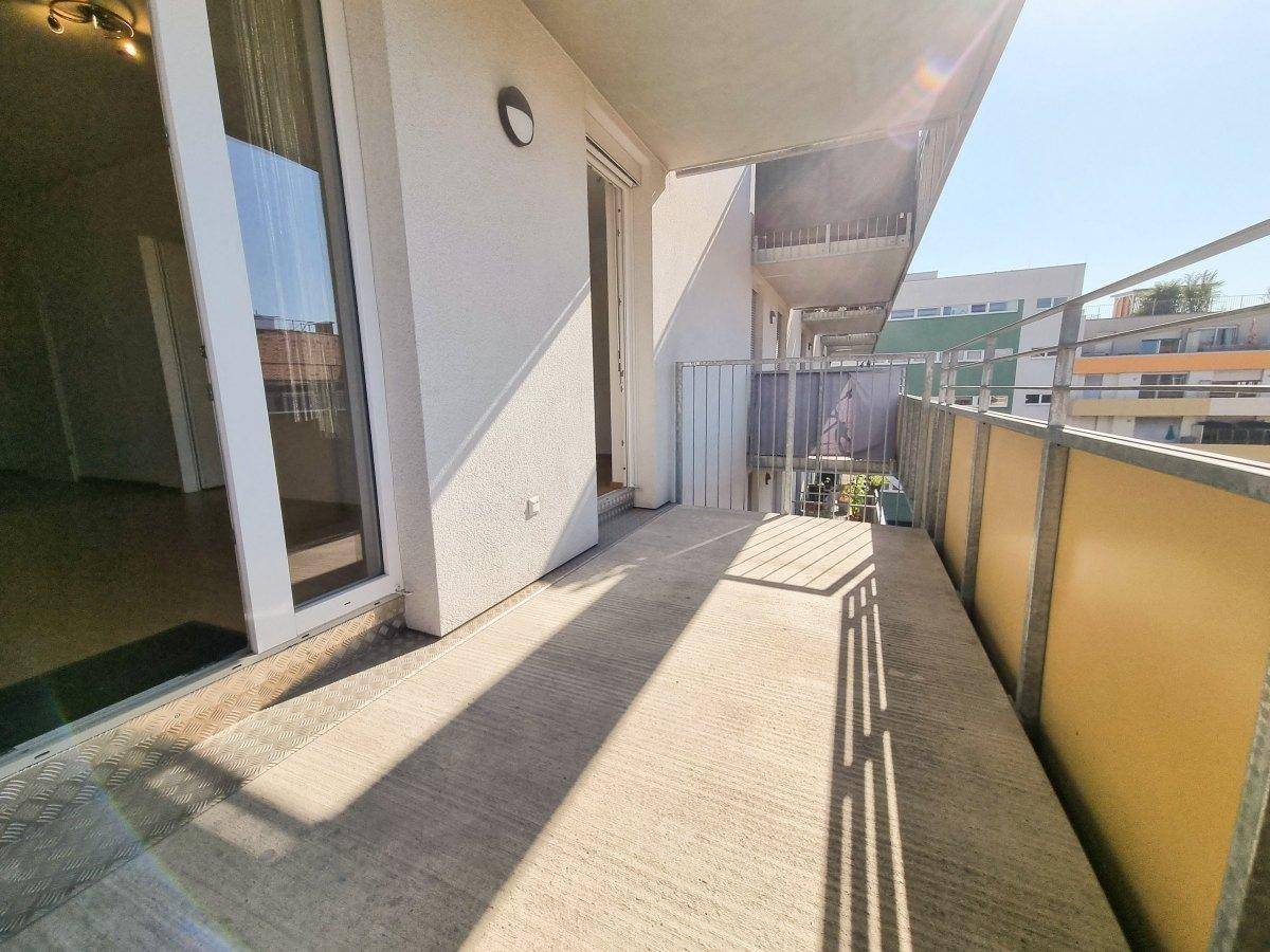 Breiter Balkon mit Betonboden und Metallgeländer, ideal für Entspannung im Freien.