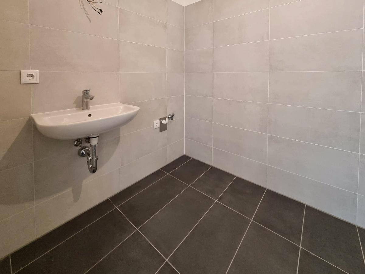 Helles Badezimmer mit modernem Waschbecken und grauen Fliesen.