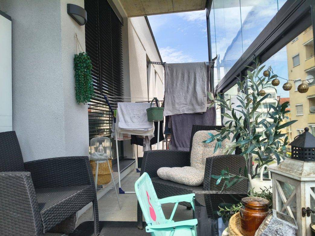 Verglaste Loggia mit Wäscheständer und Blick auf die Nachbargebäude und den Himmel.