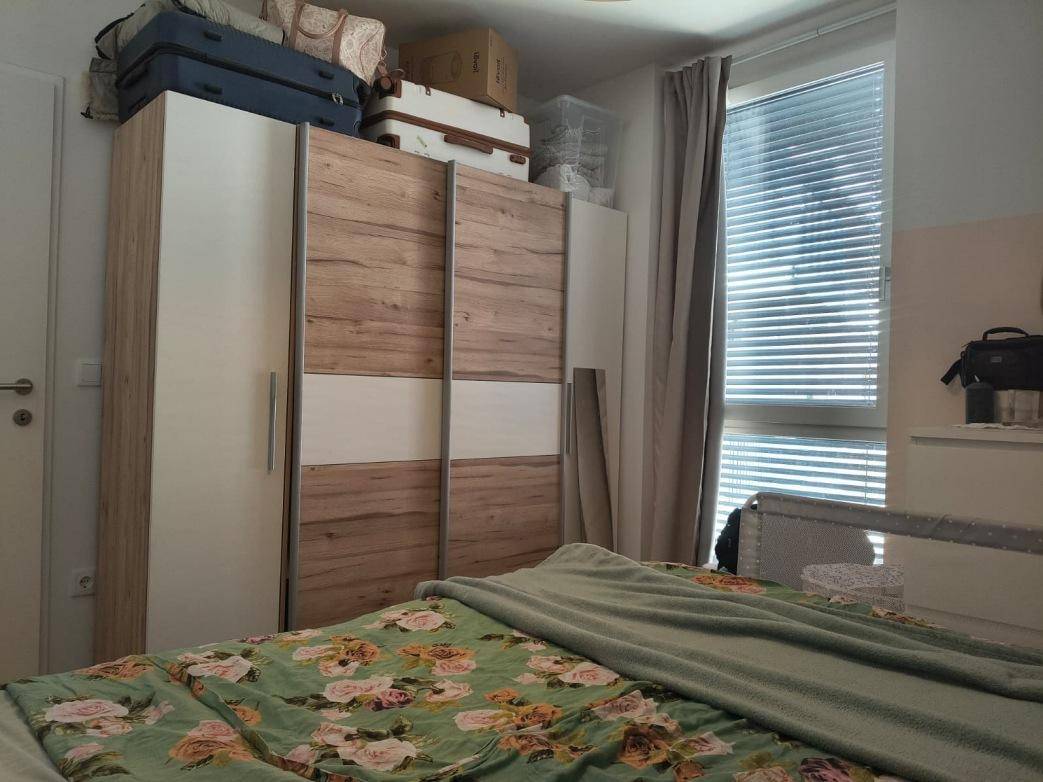 Schlafzimmer mit großem Kleiderschrank, Doppelbett und einem Fenster mit Jalousien.