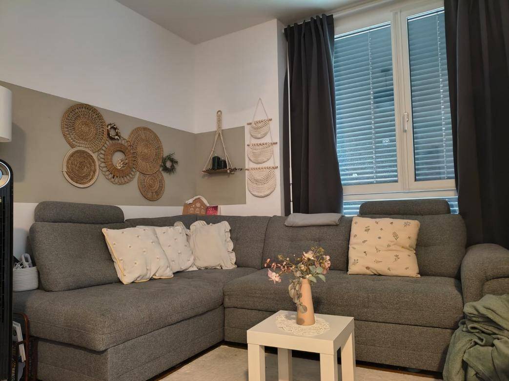 Gemütliches Ecksofa im Wohnzimmer mit dekorativen Kissen und einem kleinen Beistelltisch.